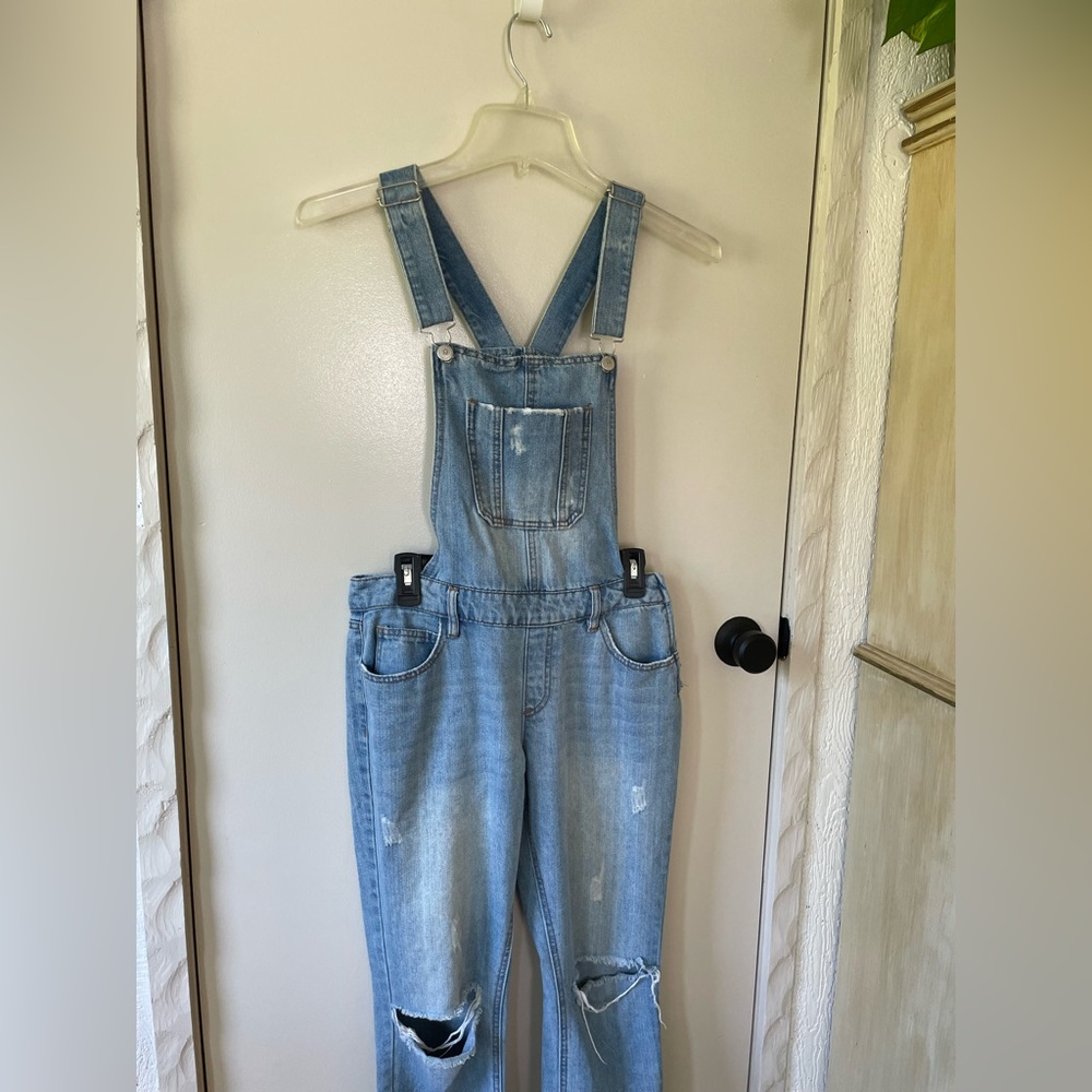 Light wash denim overalls with ripped knees.
